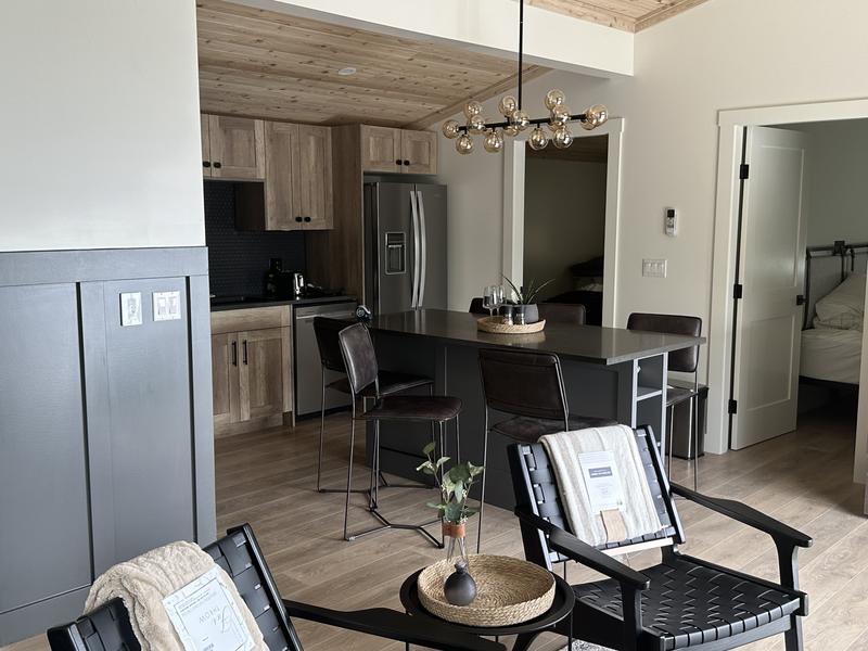 Cozy cottage interior showing a modern kitchen behind living room chairs