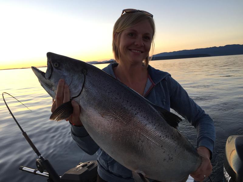 Fisherwomen holding large fish at sunset.