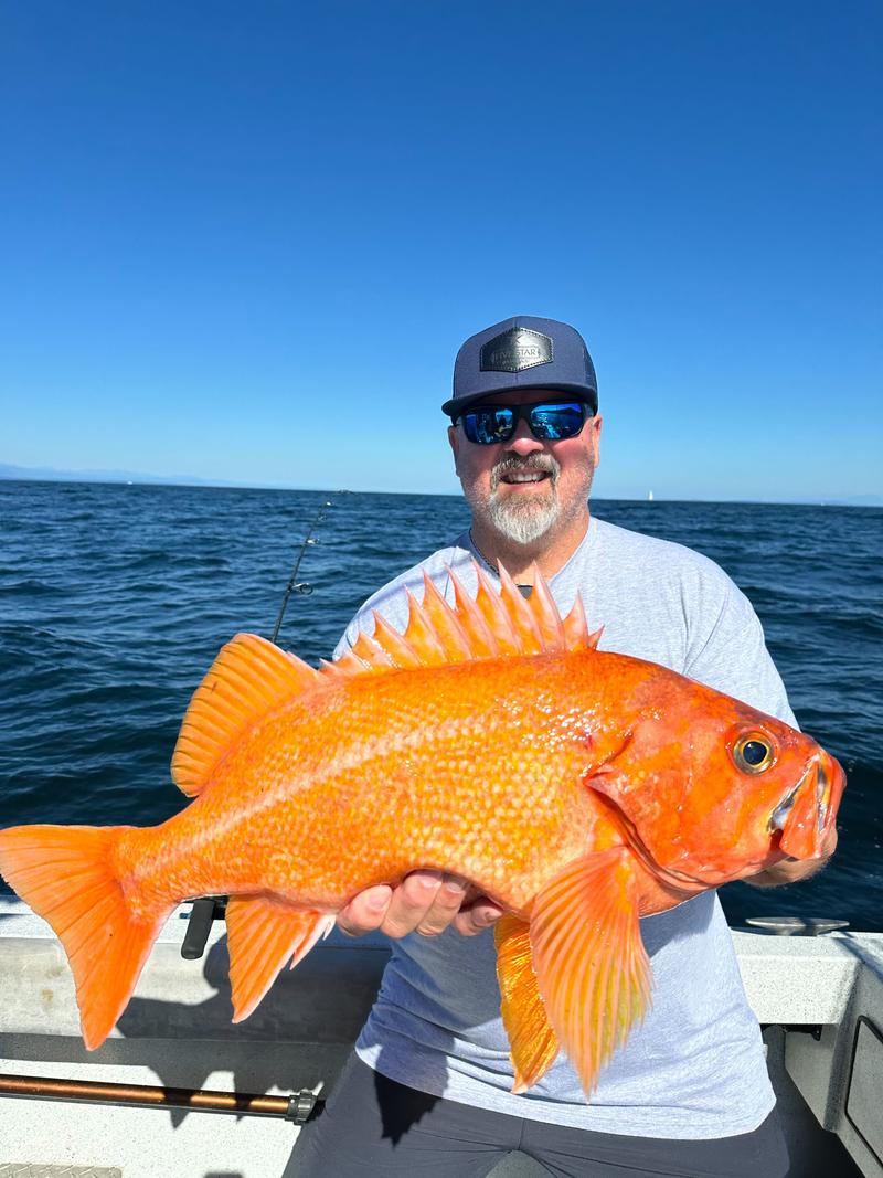 Fisherman holding a large orange fish he caught.