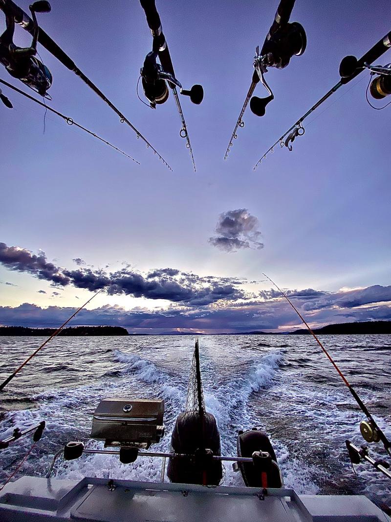 View of back of a sailing fishing boat with rods visible..