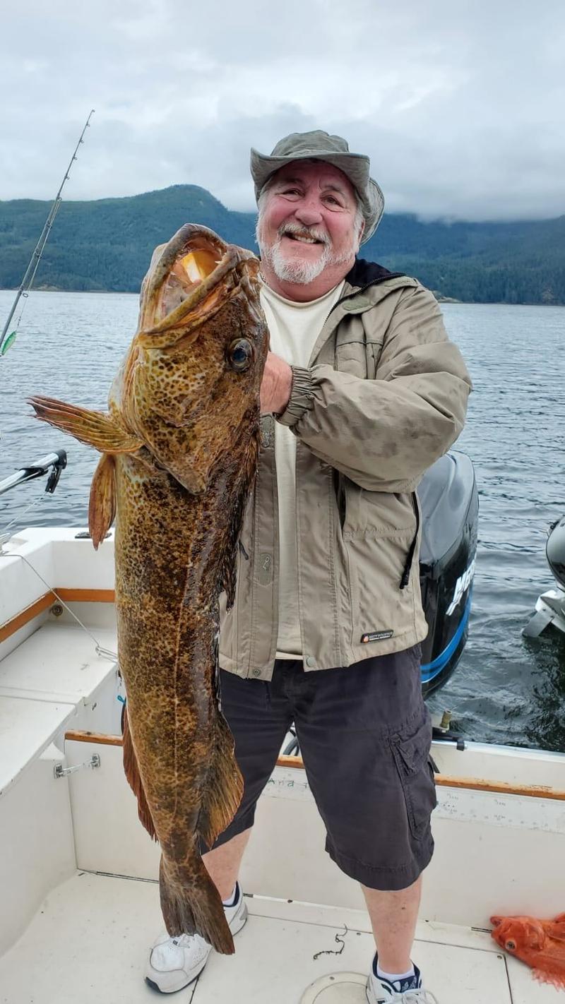 Man on fishing boat holding large catch.