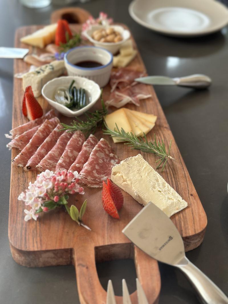 A wooden charcuterie board filled with cured meats, cheeses, fruits, and crackers.